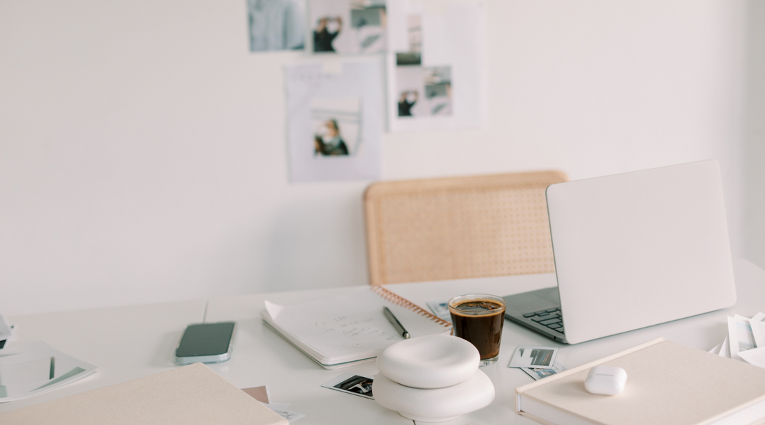 desk workspace of an interior design studio owner featuring a laptop, coffee, and moodboard